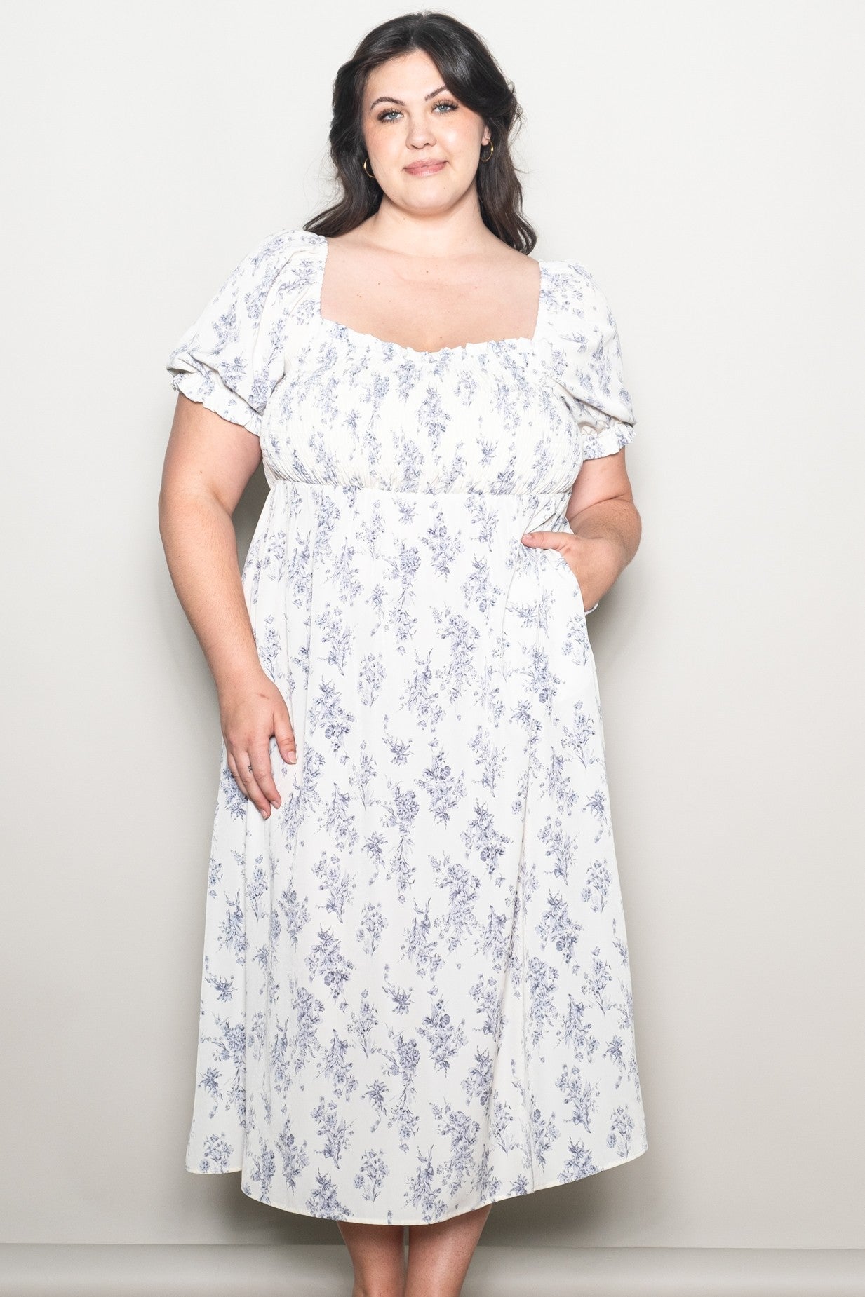 woman wearing a white floral plus-size midi dress with short puff sleeves and pockets
