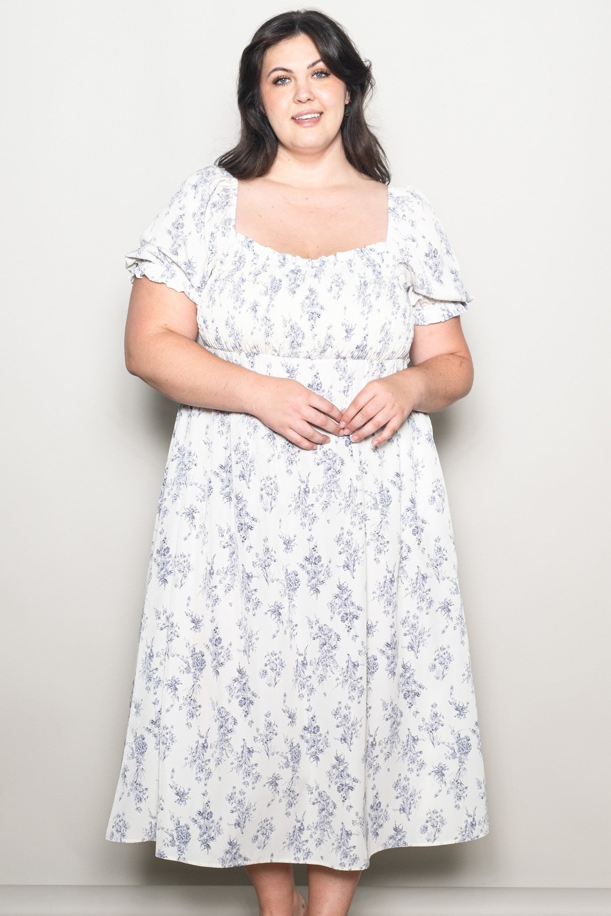 woman wearing a white floral plus-size tea dress with short puff sleeves and a square neckline