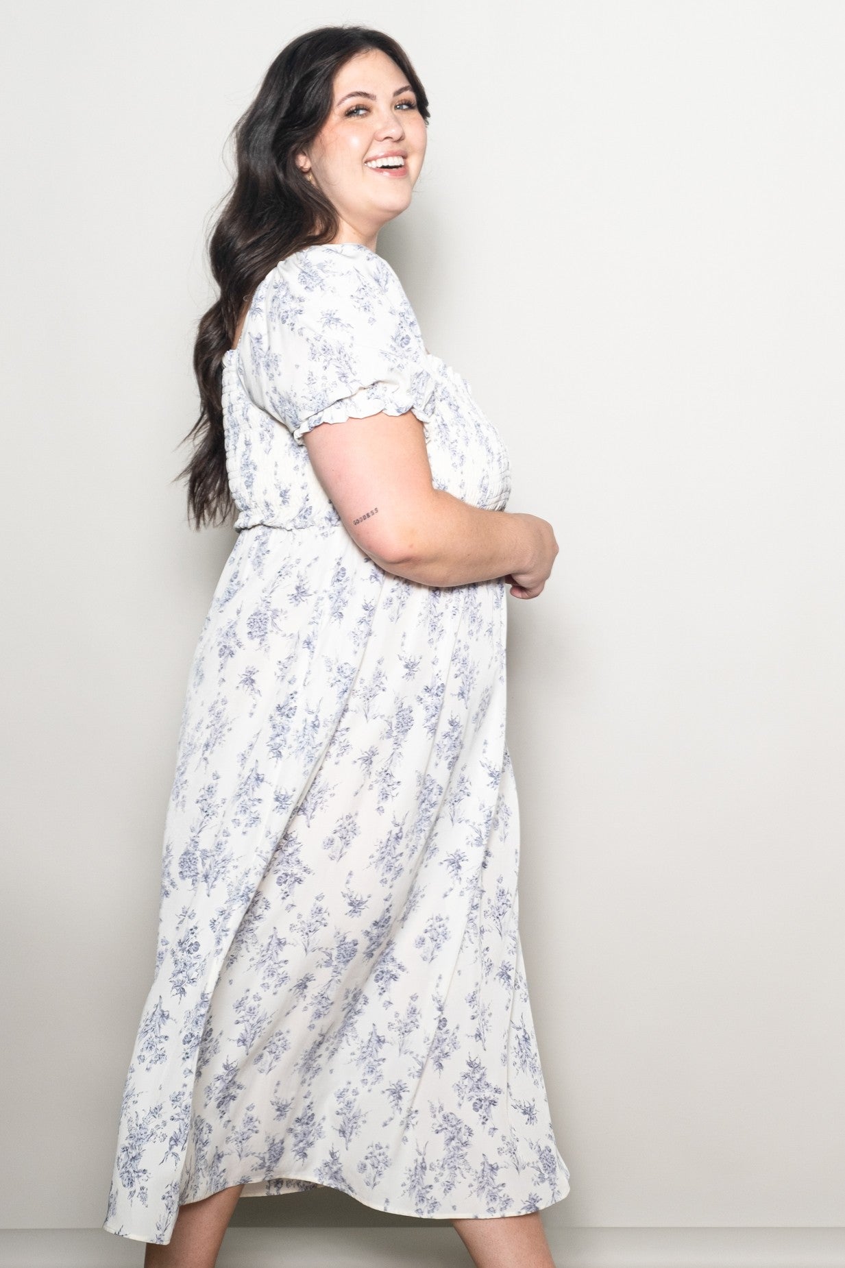 woman wearing a white floral print plus-size midi dress with short puff sleeves and a flowy silhouette