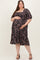 woman wearing a black floral maternity dress with puff sleeves and a tiered skirt, holding her baby bump