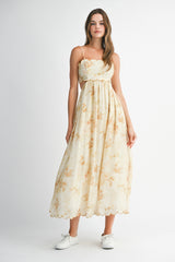 woman wearing a light yellow floral maxi dress with spaghetti straps and scalloped edges