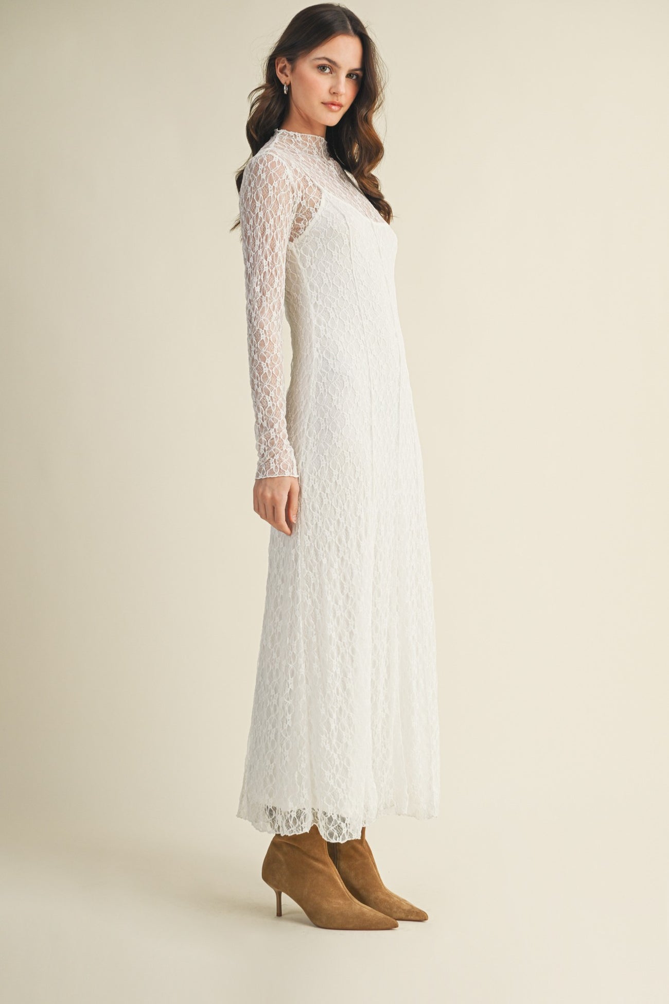woman wearing a long sleeve white lace maxi dress and tan heeled boots