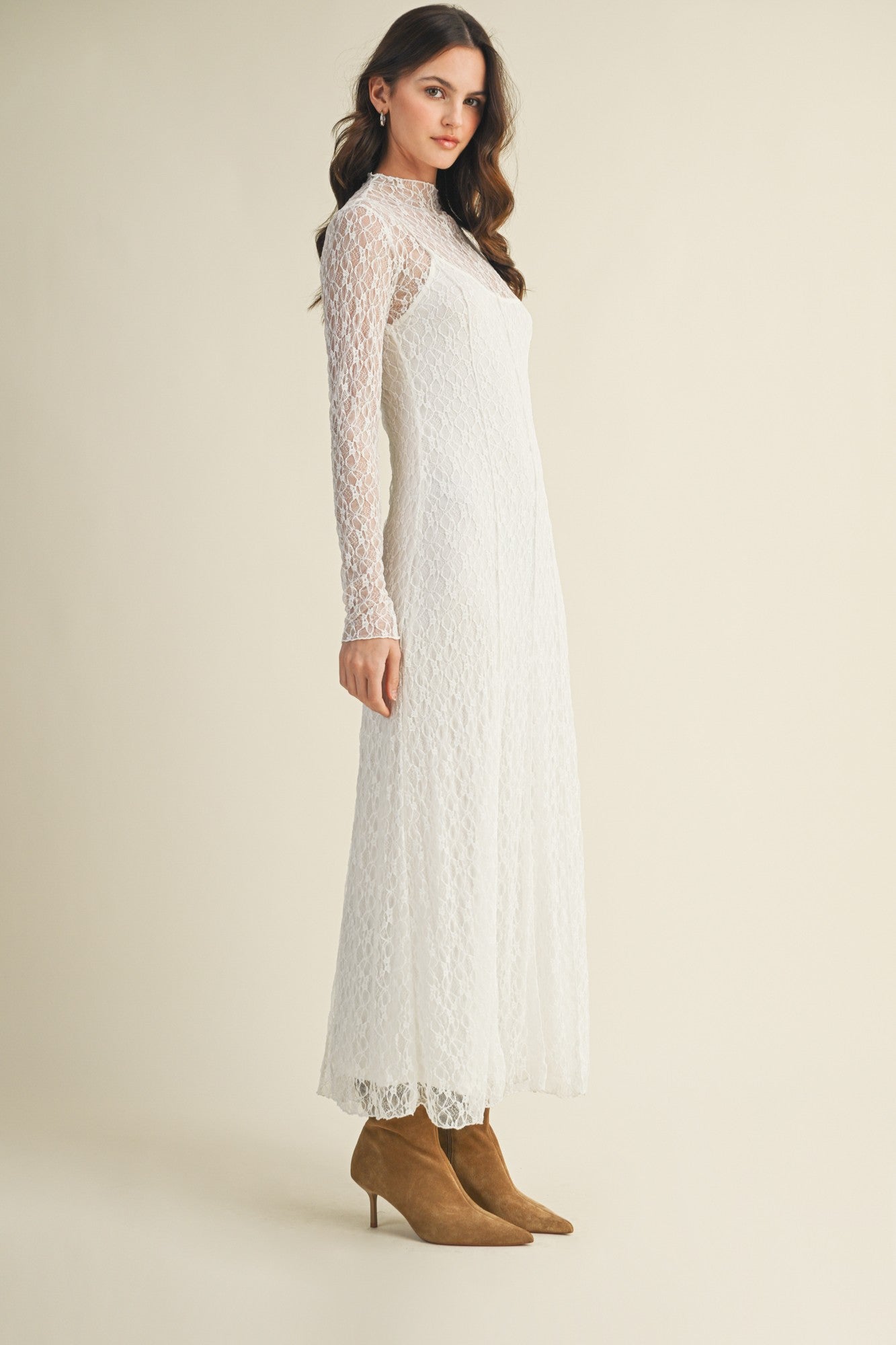 woman wearing a long sleeve white lace maxi dress and tan heeled boots