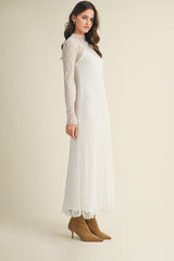 woman wearing a long sleeve white lace maxi dress and tan heeled boots