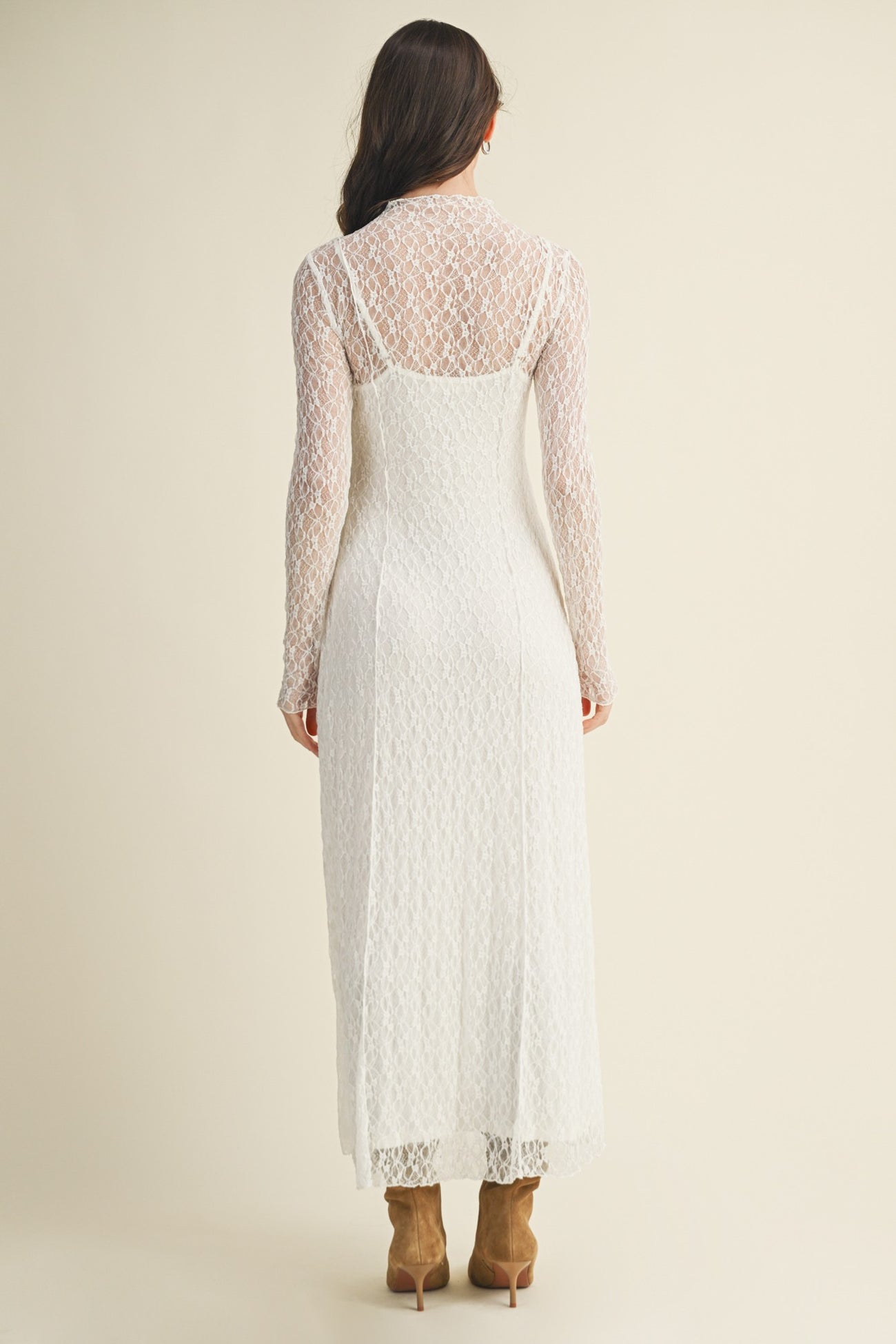 woman wearing a white lace long sleeve midi dress with a fitted silhouette and a back-zip closure