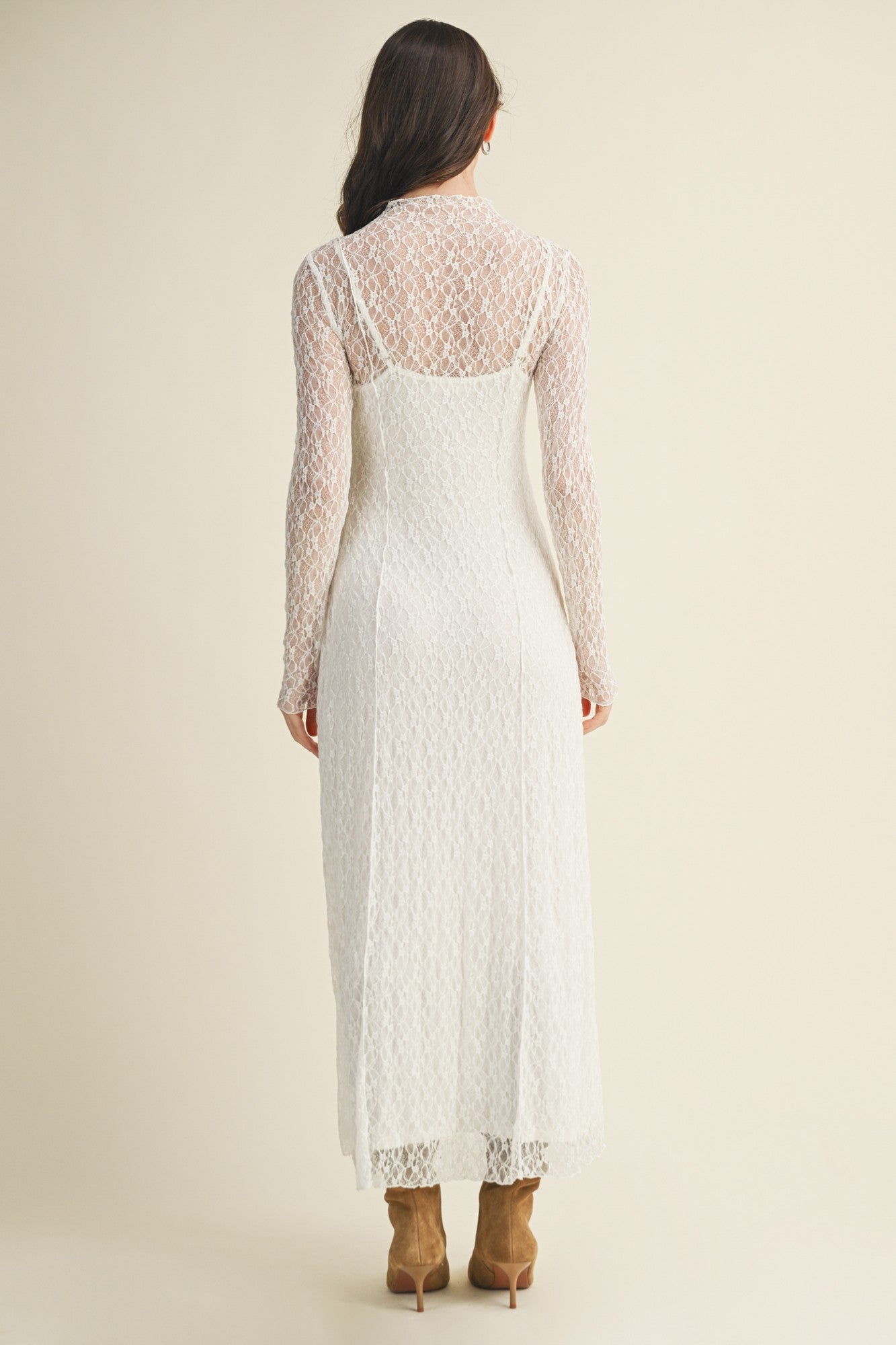 woman wearing a white lace long sleeve midi dress with a fitted silhouette and a back-zip closure