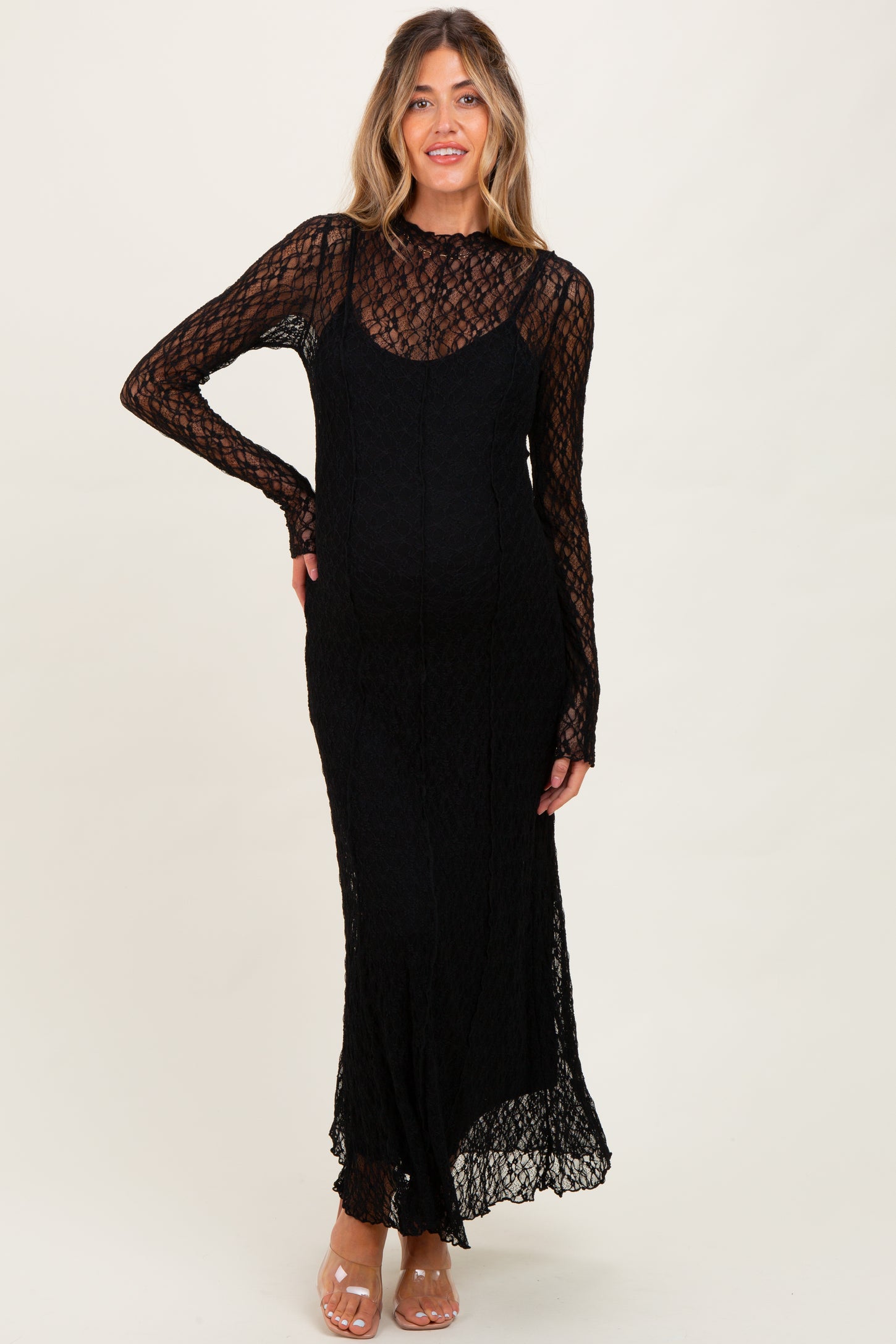 woman wearing a black lace maternity dress with long sleeves and a fitted silhouette, showcasing her baby bump