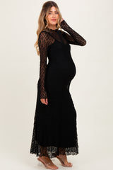 woman wearing a black lace maternity dress with long sleeves and a flowing skirt, showcasing her baby bump