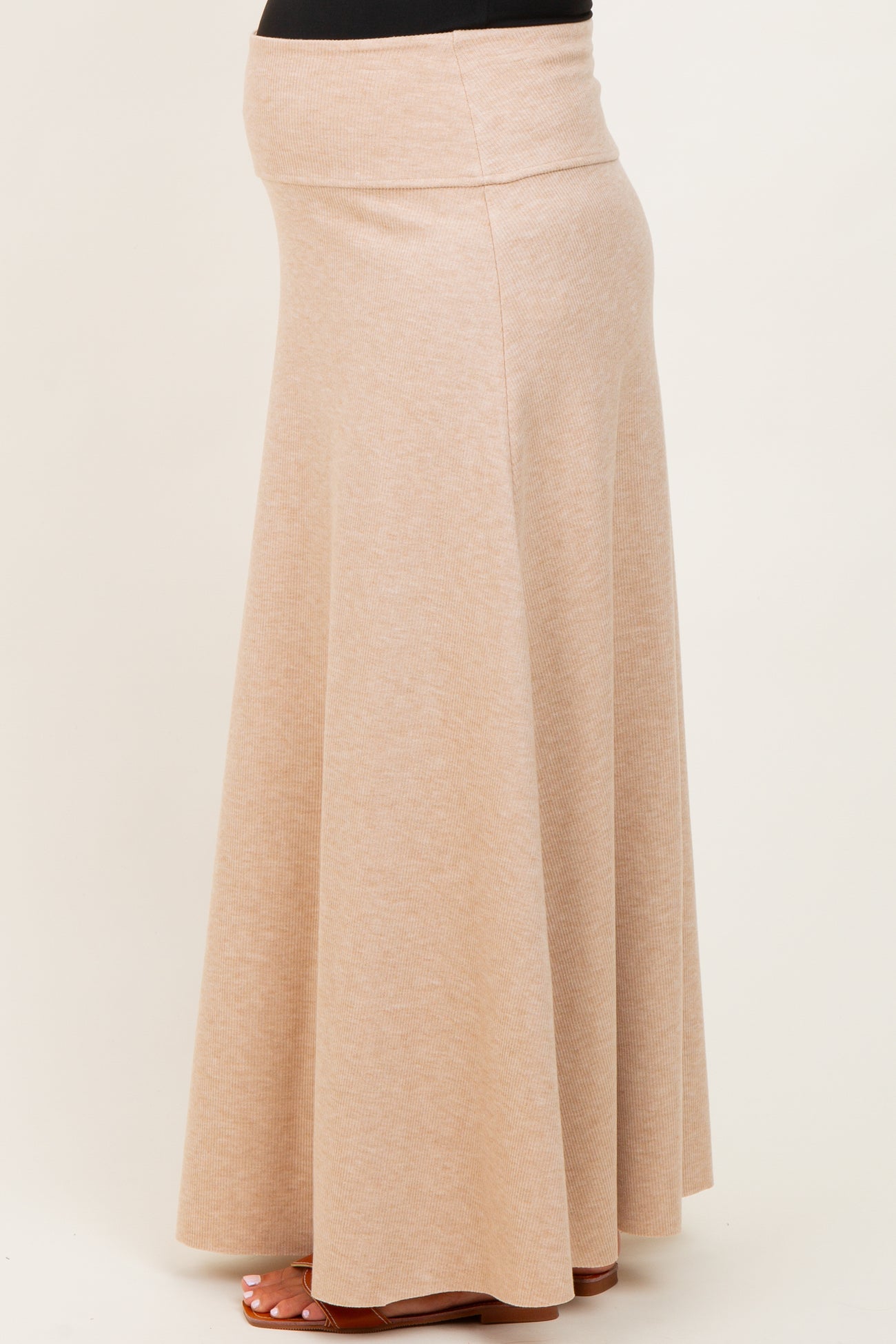 woman wearing a beige maternity maxi skirt with a stretchy waistband and flowing design, showing a baby bump
