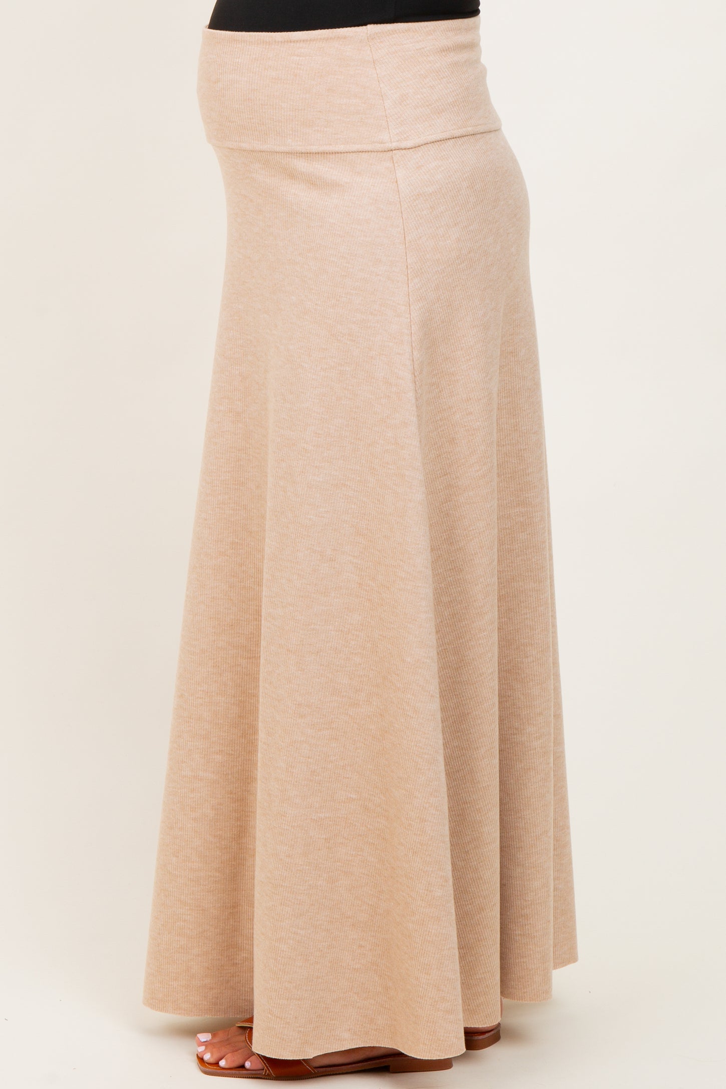 woman wearing a beige maternity maxi skirt with a stretchy waistband and flowing design, showing a baby bump
