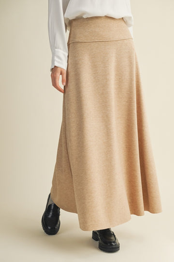 woman wearing a beige maxi skirt with a flared silhouette and paired with black ankle boots