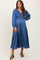woman wearing a satin blue maternity dress with a smocked bodice and long puff sleeves, showcasing her baby bump