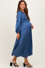 woman wearing a navy blue maternity dress with pleated skirt and balloon sleeves, showing her baby bump