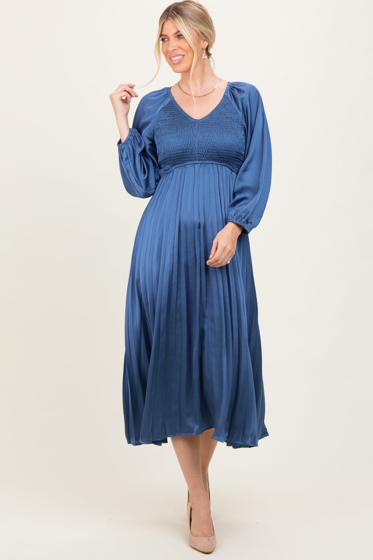 woman wearing a dark blue pleated long sleeve dress with a smocked bodice and v-neckline
