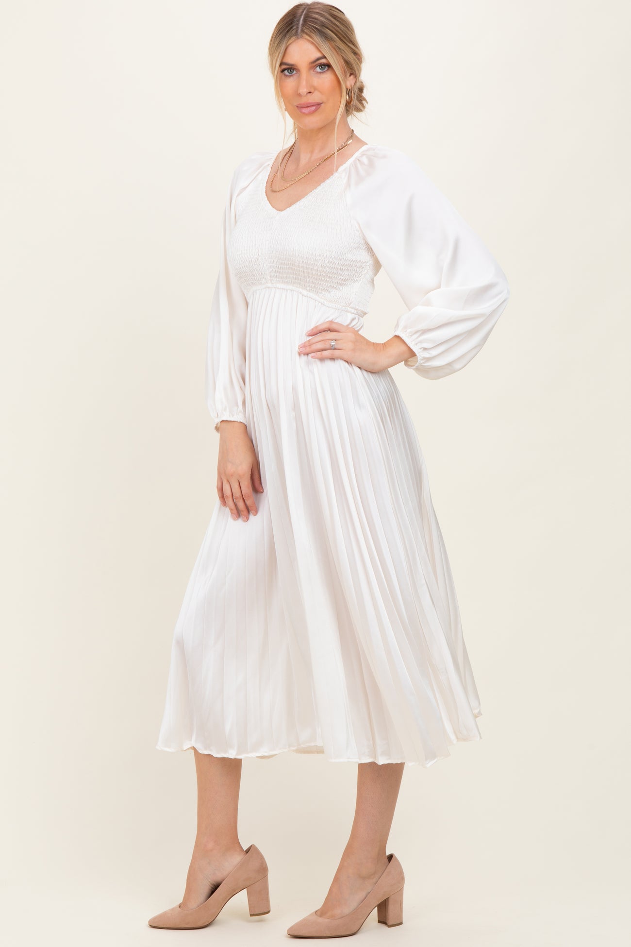 woman wearing a white midi dress with puff sleeves and smocked bodice, paired with light tan heels