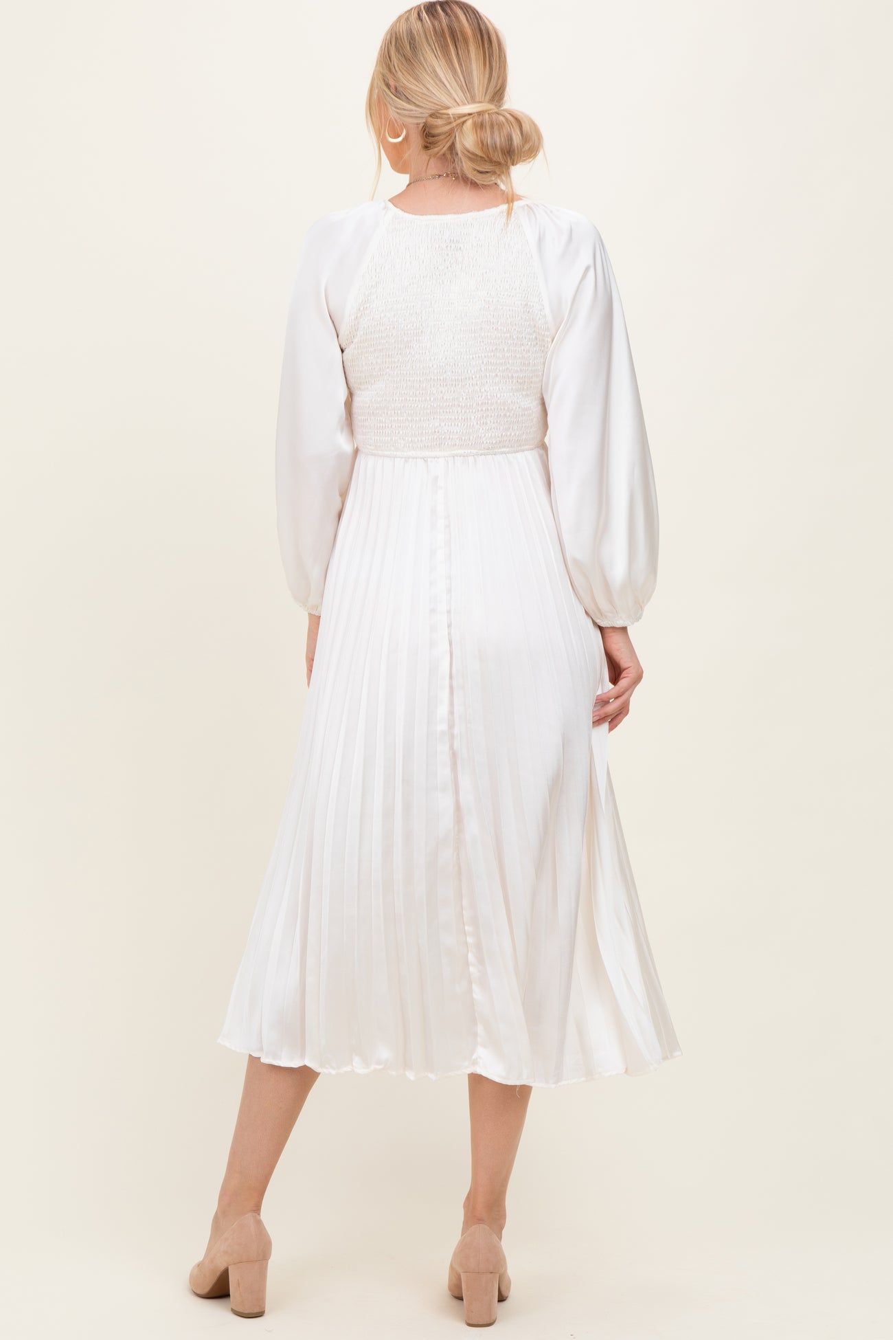 woman wearing a white midi dress with a smocked bodice and pleated skirt, shown from the back