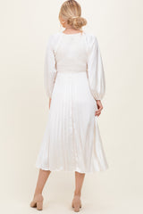 woman wearing a white midi dress with a smocked bodice and pleated skirt, shown from the back
