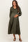 woman wearing an olive green pleated maternity dress with a smocked bodice and long sleeves, holding her baby bump