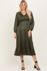 woman wearing an olive green pleated midi dress with puff sleeves and a fitted bodice
