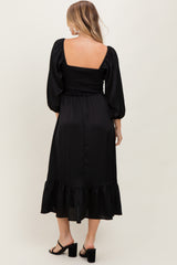 woman wearing a black puff sleeve midi dress with a smocked bodice and ruffle hem, shown from the back