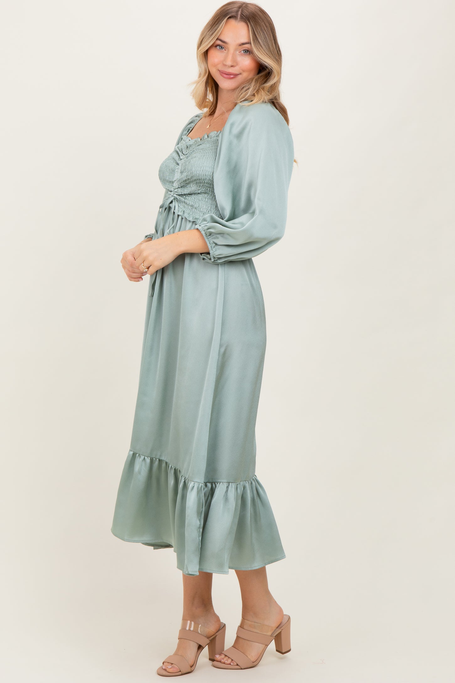 woman wearing a sage green smocked midi dress with ruffled hem and long sleeves
