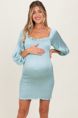 woman wearing a light blue maternity dress with ruffled neckline and puff sleeves, showcasing her baby bump