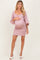 woman wearing a mauve maternity dress with puff sleeves and a fitted skirt, highlighting her baby bump