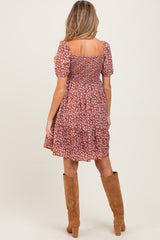 woman wearing a floral red maternity dress with short sleeves and a smocked bodice, viewed from the back