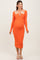 woman wearing an orange ribbed maternity dress with a keyhole cutout and long sleeves, showcasing her baby bump