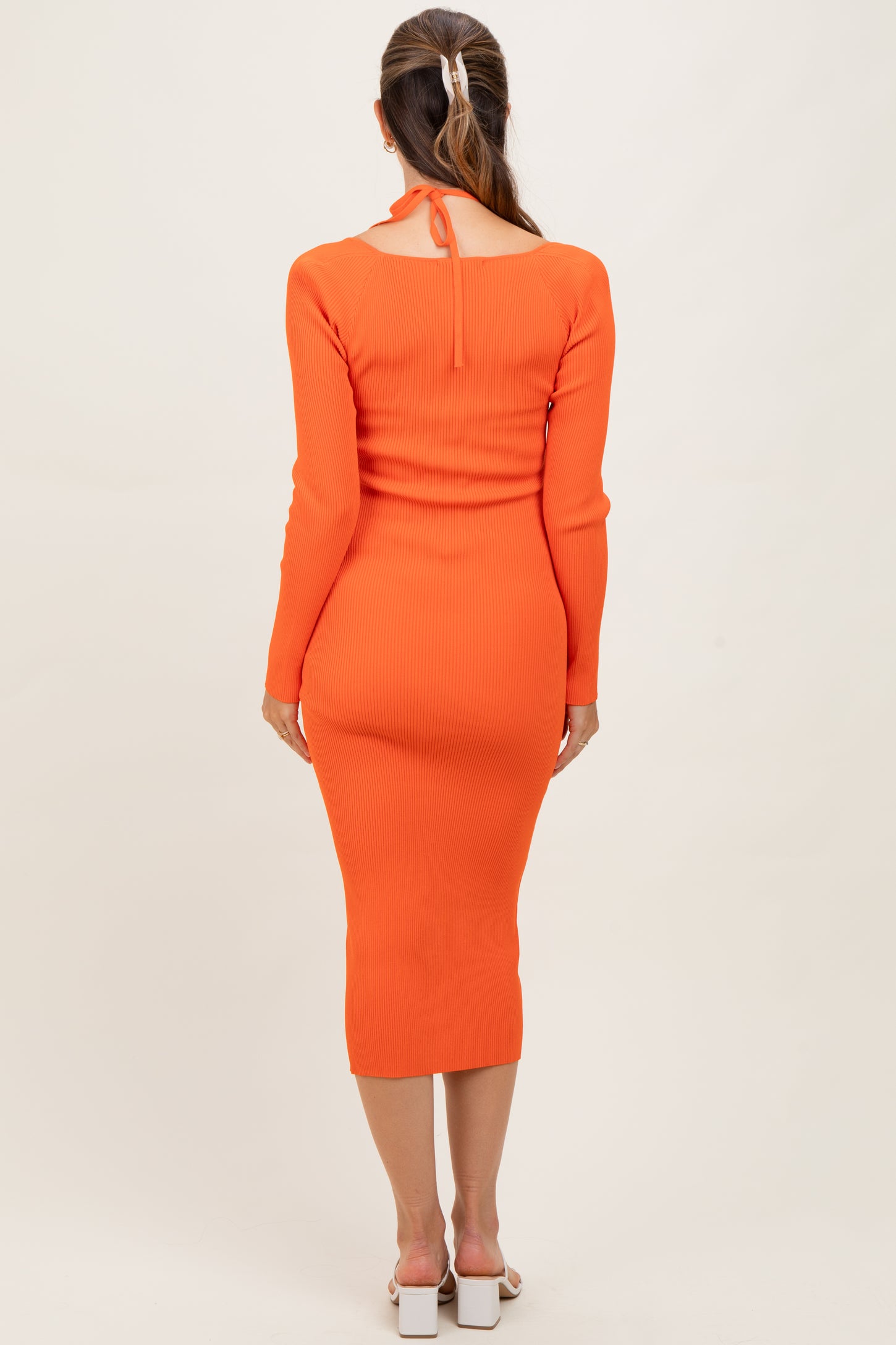 woman wearing a bright orange ribbed maternity dress with long sleeves and a tie detail at the back