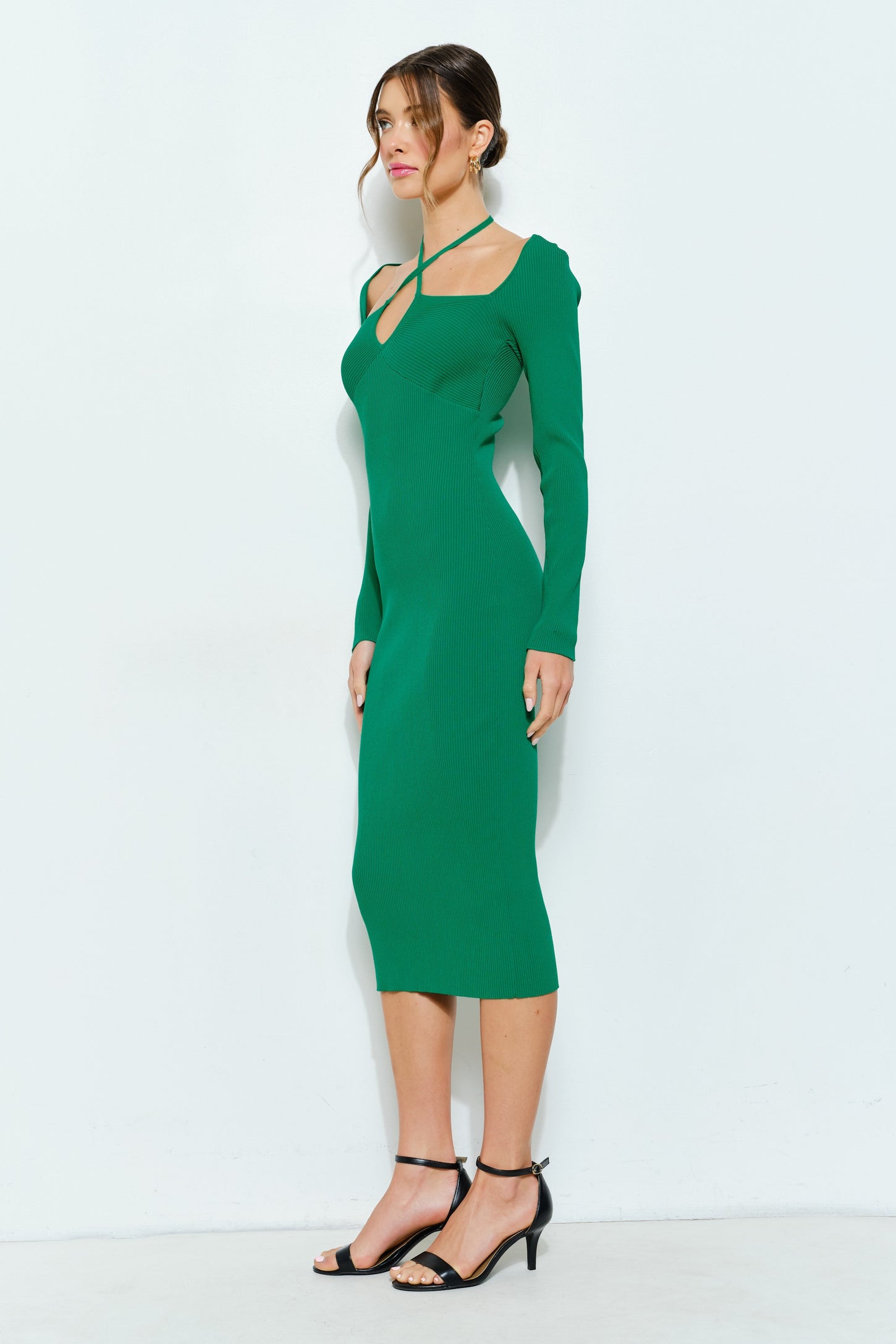 woman wearing a fitted green ribbed midi dress with long sleeves and a crisscross neckline detail