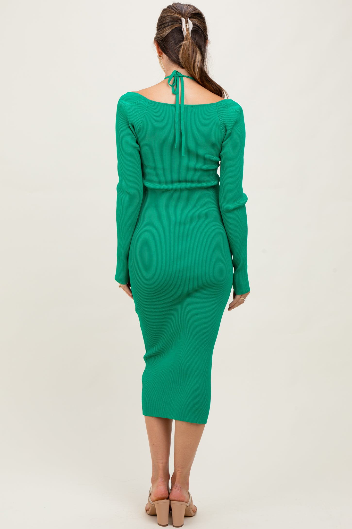 woman wearing a green ribbed maternity dress with a back tie detail, fitted style, showing a baby bump