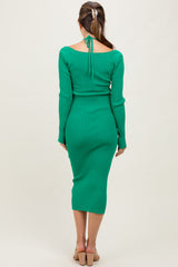 woman wearing a green ribbed maternity dress with a back tie detail, fitted style, showing a baby bump