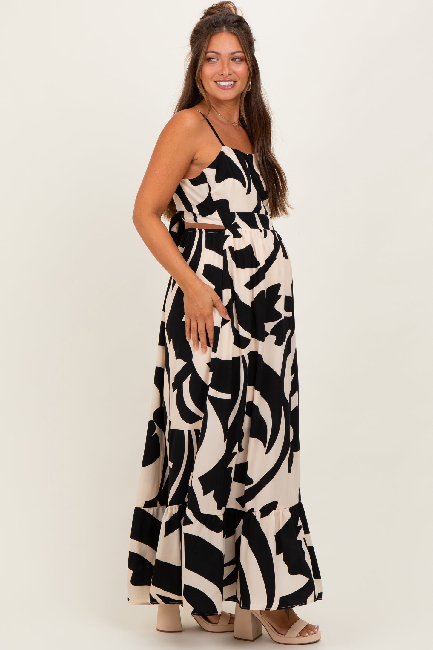 woman wearing a black and cream abstract print maternity maxi dress with a fitted bodice and flowing skirt, showing a baby bump