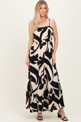 woman wearing a black and cream maxi dress with abstract print and tiered hem, standing and smiling