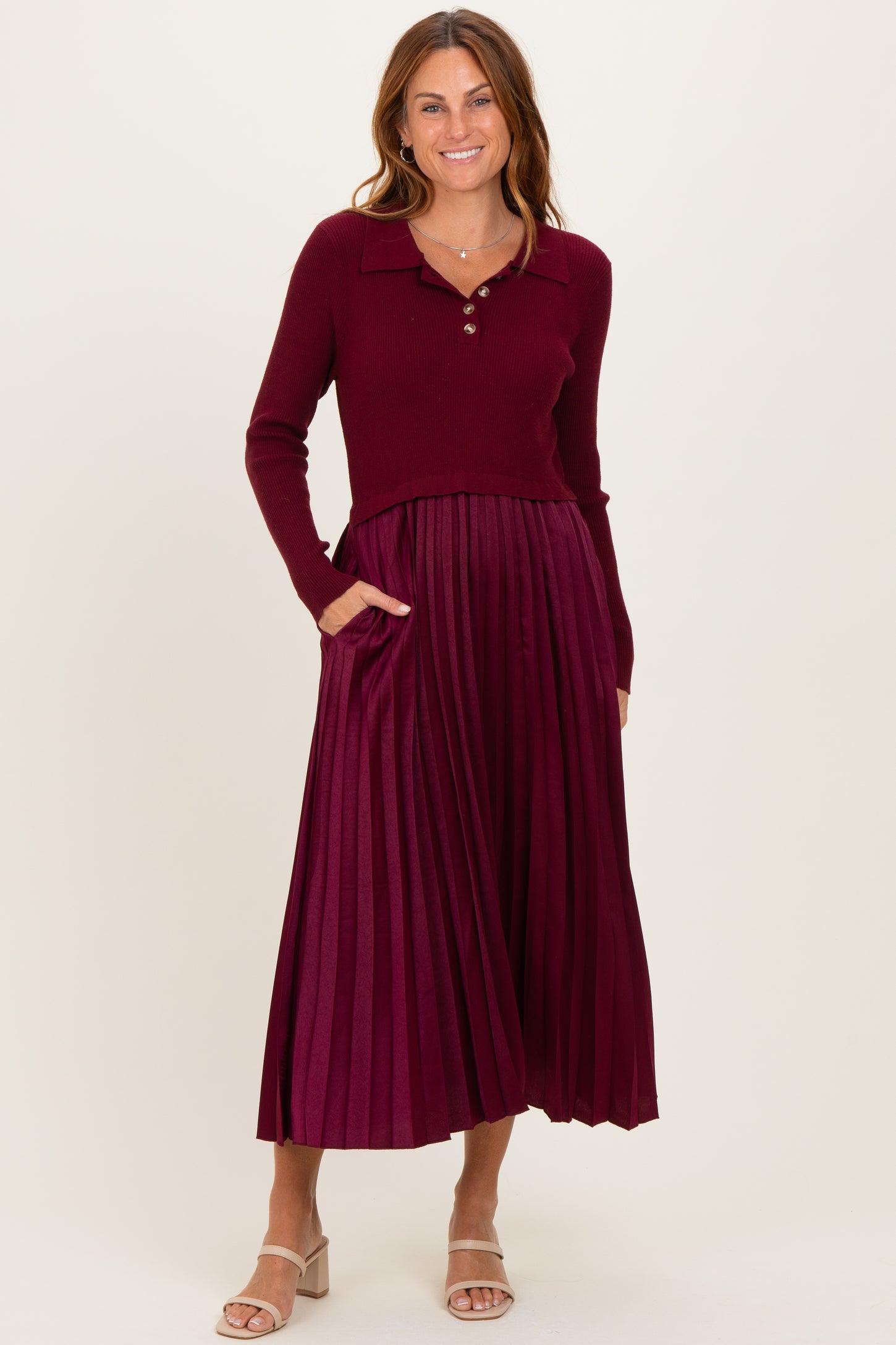 woman wearing a burgundy ribbed sweater with a collared neckline and a pleated midi skirt with pockets