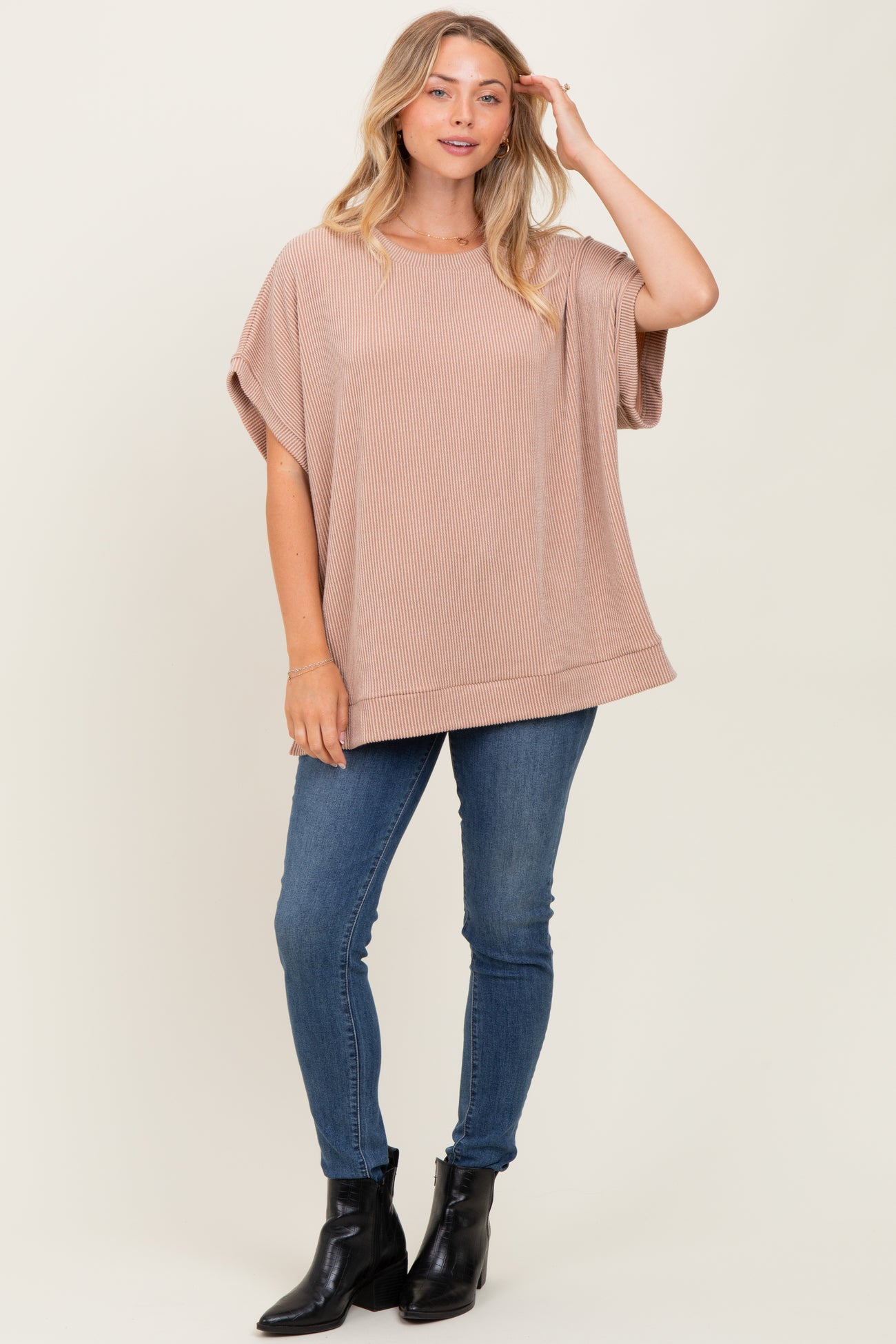 woman wearing a ribbed beige oversized t-shirt with short sleeves and blue skinny jeans