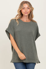 woman wearing a relaxed fit olive green ribbed knit top with short sleeves and side slits, paired with jeans