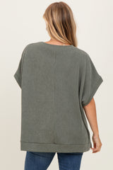 woman wearing a loose-fitting green ribbed top with short sleeves and a rounded hem, seen from the back