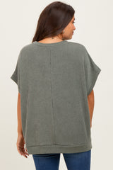 woman wearing a loose-fit olive green ribbed maternity top, shown from the back with short sleeves