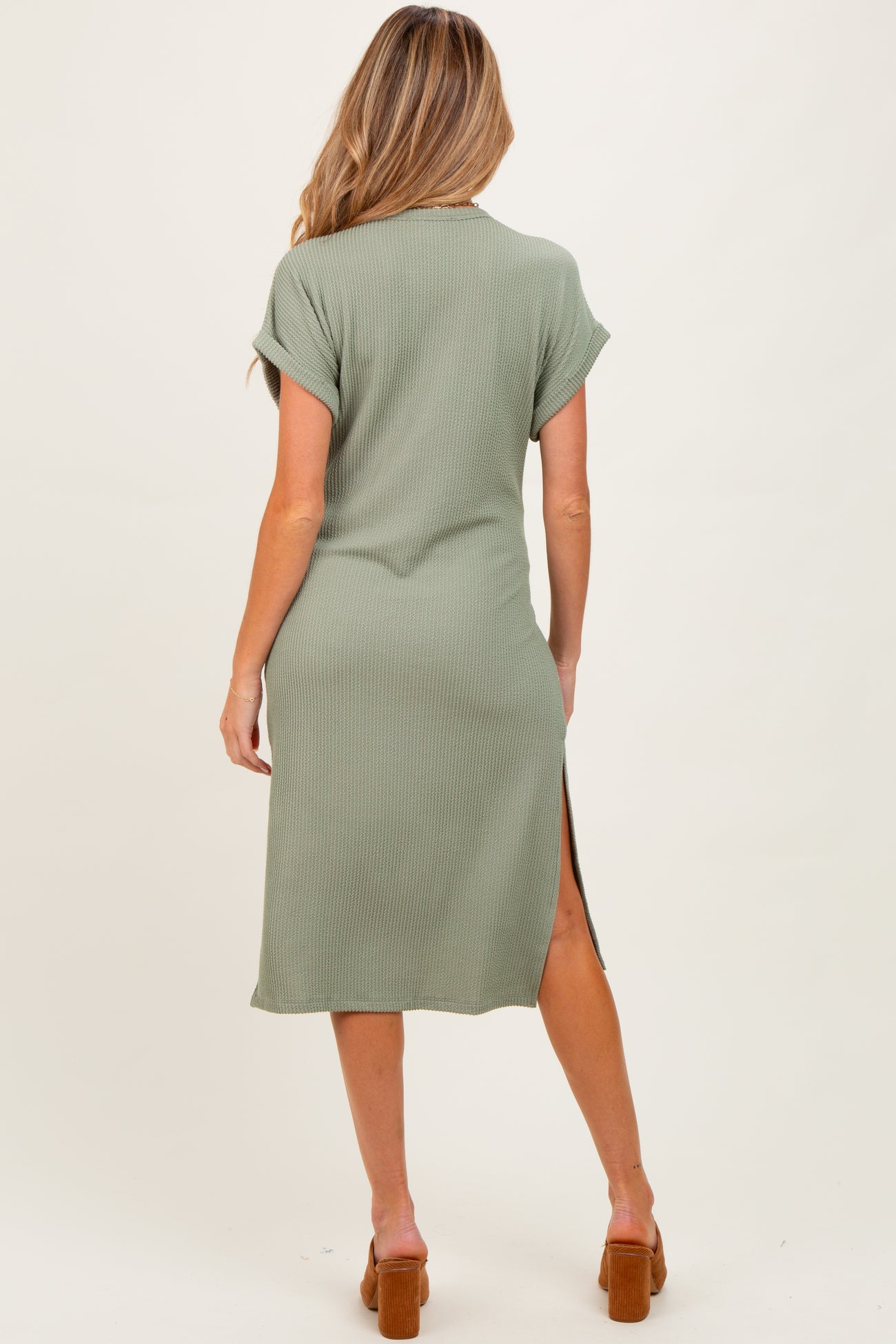 woman wearing a green short sleeve ribbed maternity dress with a side slit