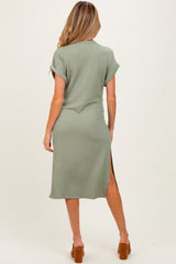 woman wearing a green short sleeve ribbed maternity dress with a side slit