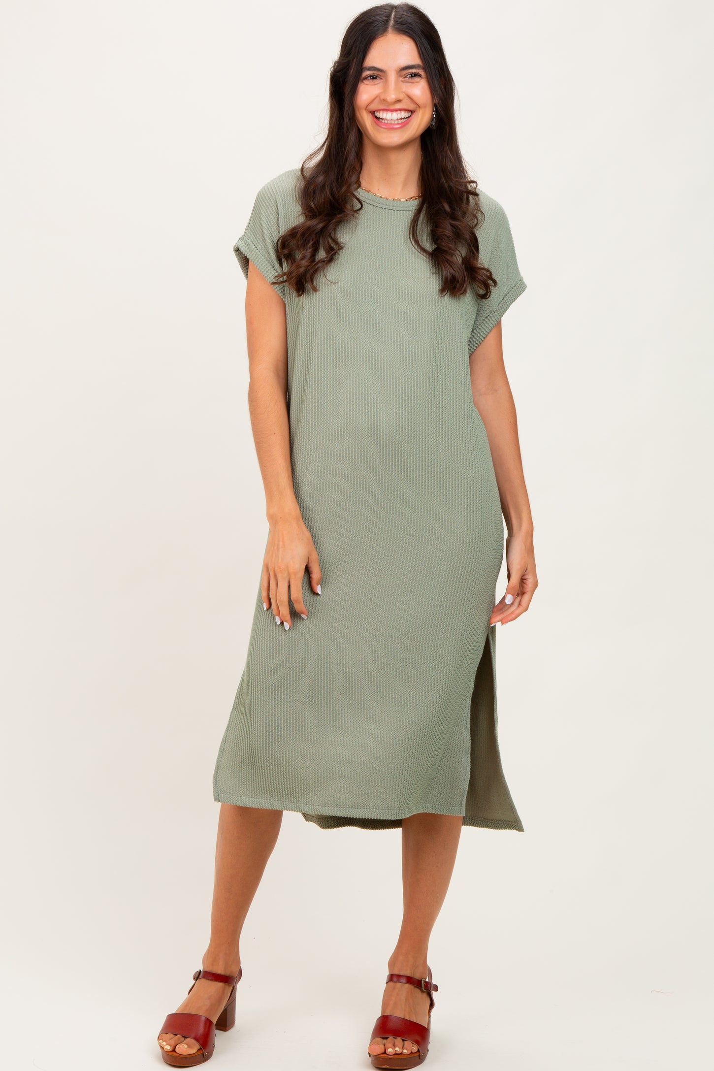 woman wearing a sage green short sleeve midi dress with side slits and a relaxed fit