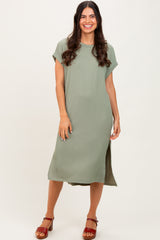 woman wearing a sage green short sleeve midi dress with side slits and a relaxed fit