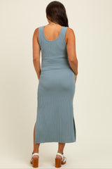 woman wearing a ribbed blue maternity maxi dress with side slits and a fitted silhouette