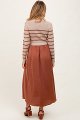 woman wearing a striped long sleeve maternity sweater and a flowy maxi skirt in rust color, with baby bump visible
