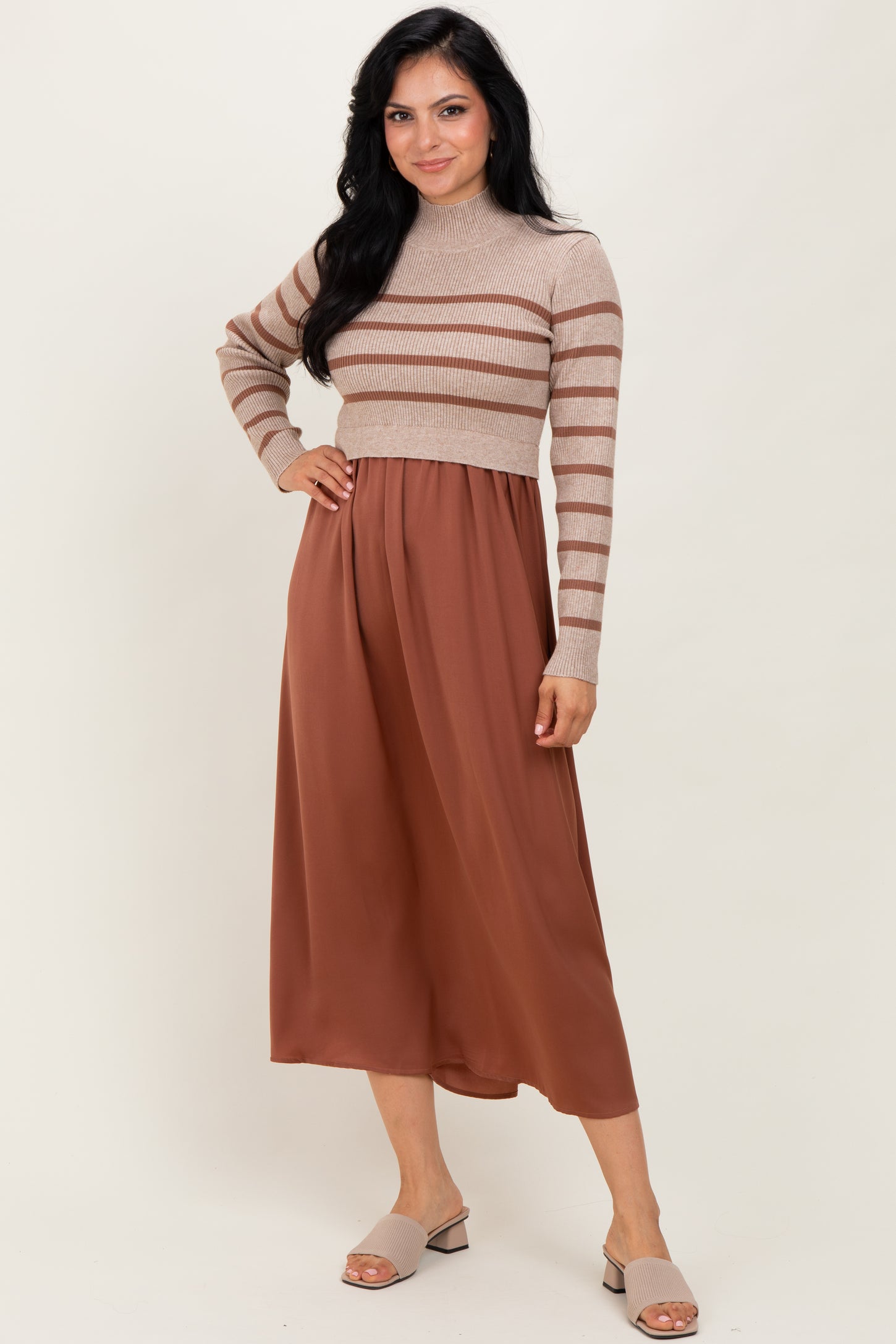 woman wearing a beige and rust striped cropped sweater and a rust pleated midi skirt with slip-on sandals