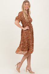 woman wearing a rust floral midi dress with puff sleeves and a cinched waist, paired with nude high heels
