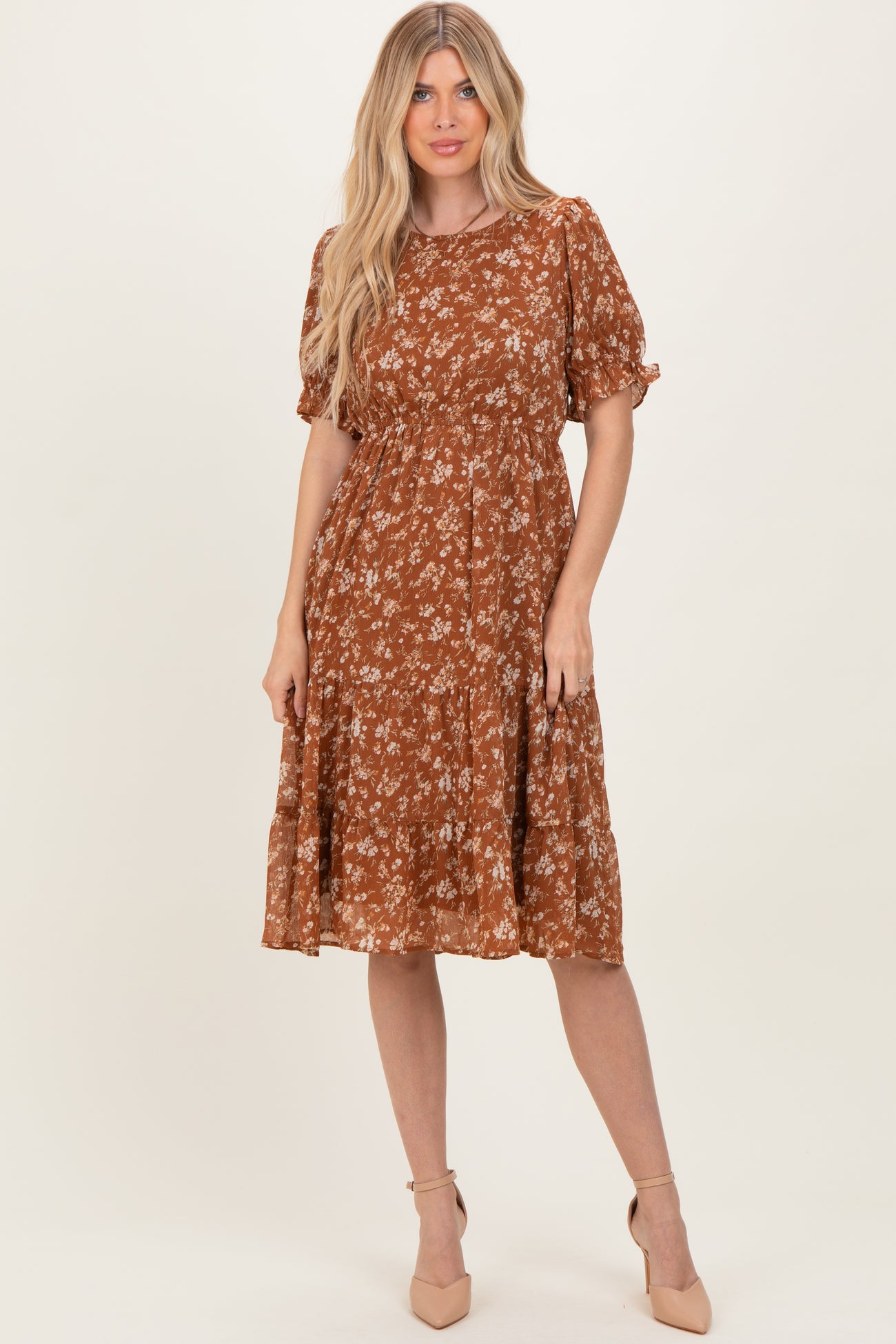 woman wearing a brown floral midi dress with puff sleeves and a tiered skirt