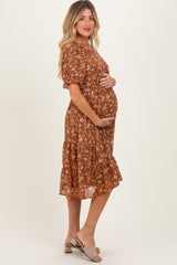 woman wearing a rust colored floral midi maternity dress and showing her baby bump
